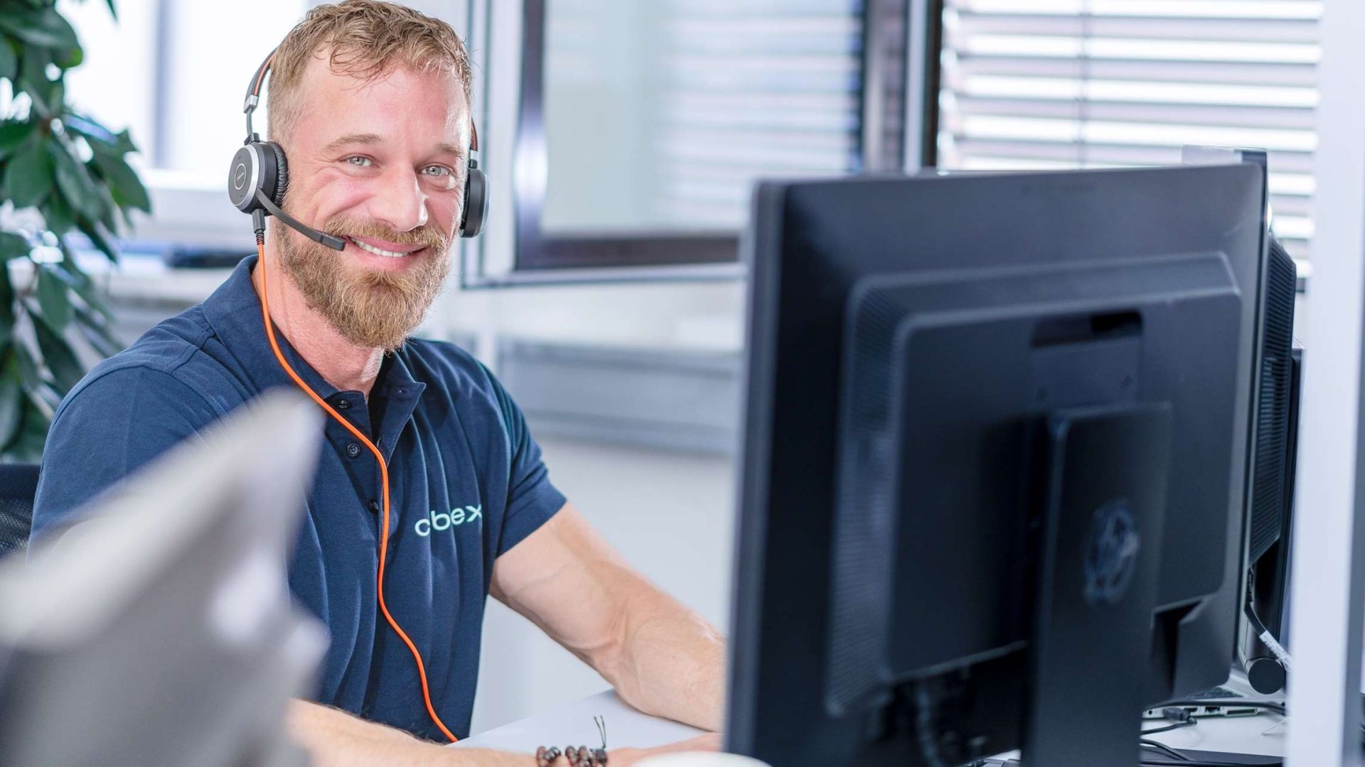 Un employé de cablex avec un casque sourit à la caméra.