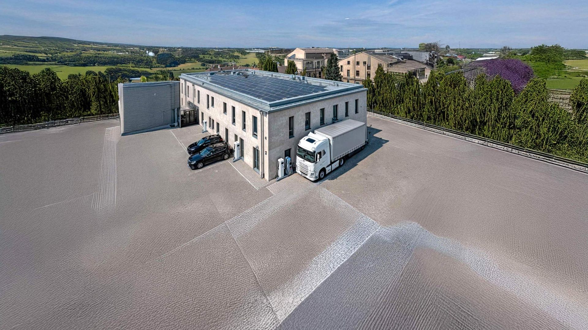 Elektrische PKW und ein elektrischer LKW vor einem Firmengebäude mit Ladestationen
