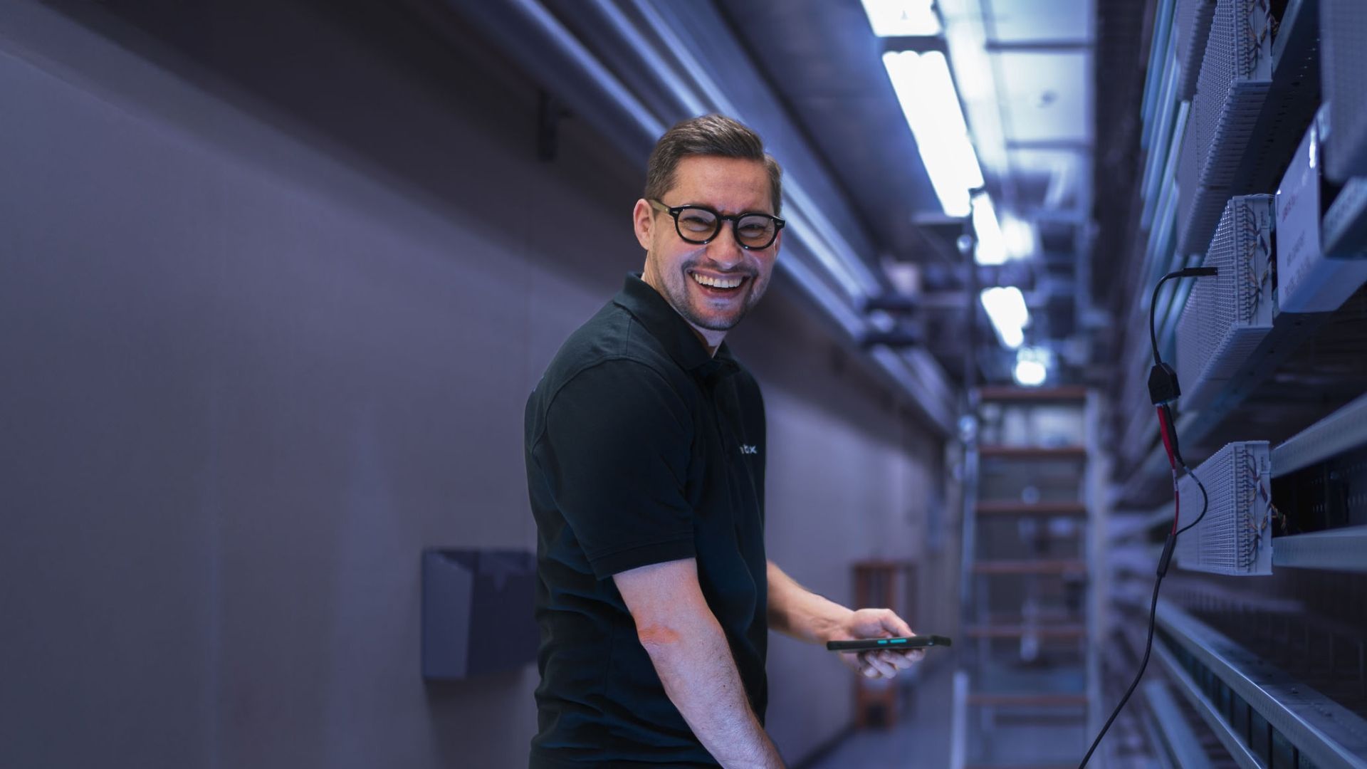 Technicien cablex dans la salle de commande, iPad à la main.