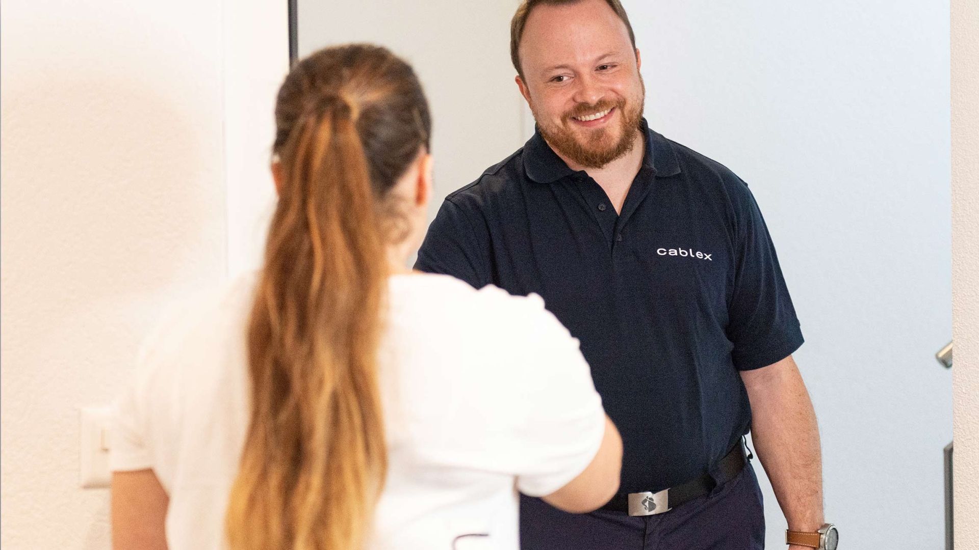 Une cliente accueille un technicien cablex à la porte.