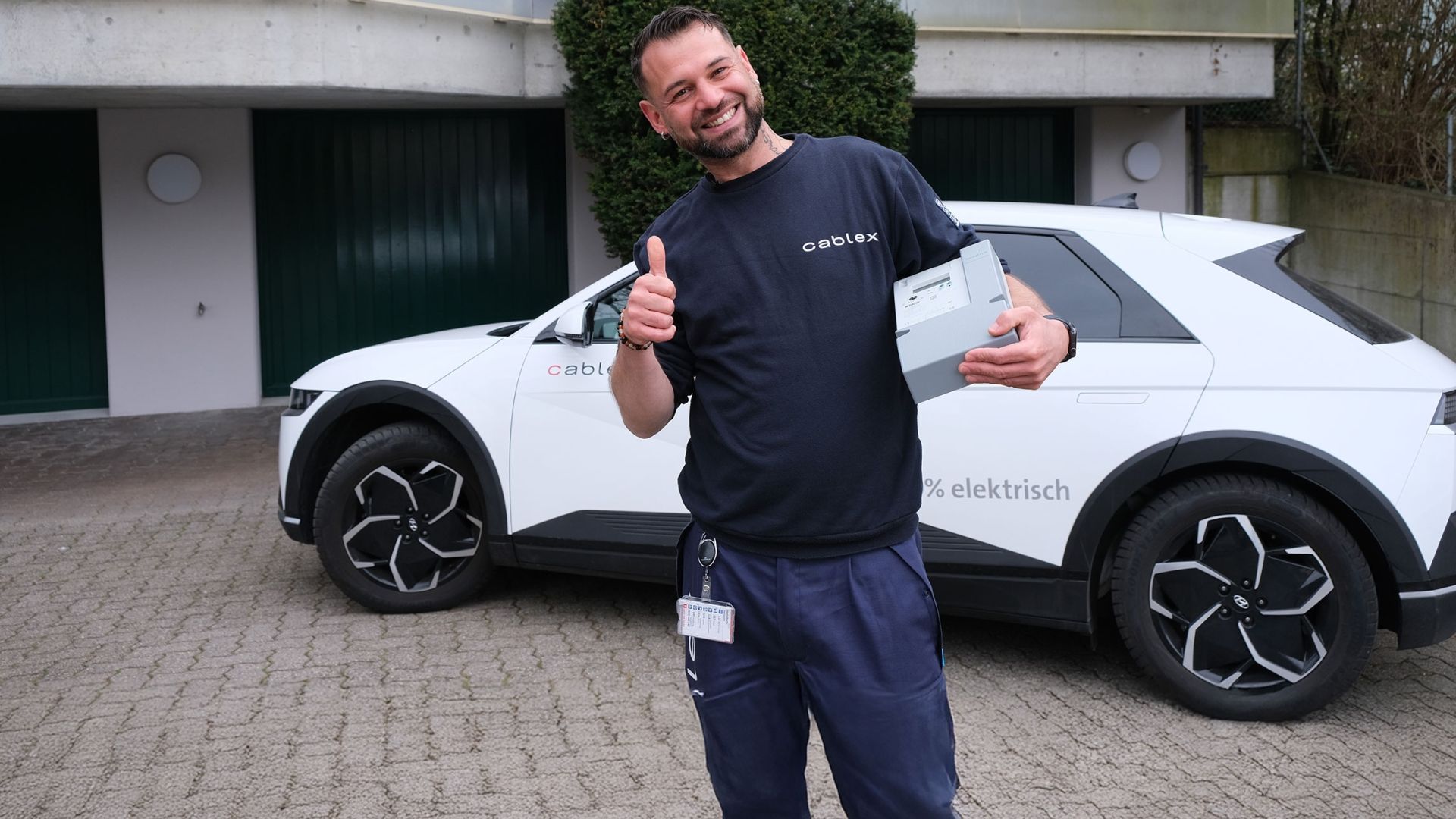 Field Service Techniker mit Smart Meter in der Hand vor seinem E-Auto