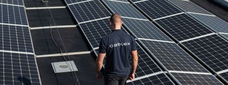 cablex Mitarbeitender steht vor Solar-Panel auf einem Dach.