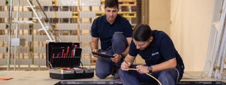 Two cablex technicians work on an electrical installation under the floor covering