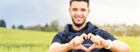 Junger Mann formt mit der Hand ein Herz über dem cablex Logo auf seinem T-Shirt.