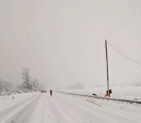 Schneesturm und schneebedeckte Strasse. Techniker repariert die Freileitung.