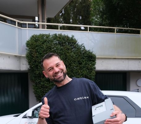 Field Service Techniker mit Smart Meter in der Hand vor seinem E-Auto