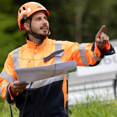 Le technicien cablex tient un plan de construction et explique la mission à l'équipe.