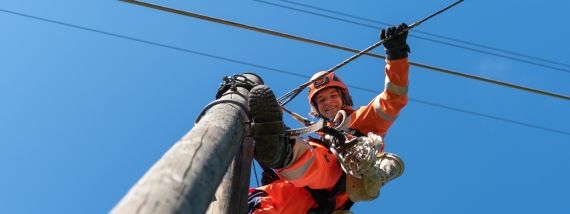 Lernender Netzelektriker arbeitet auf einem Freileitungsmast.