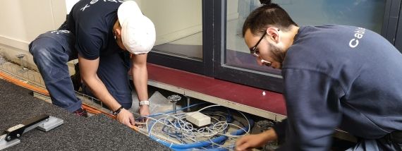 Two apprentice assembly electricians laying cable in a company building.